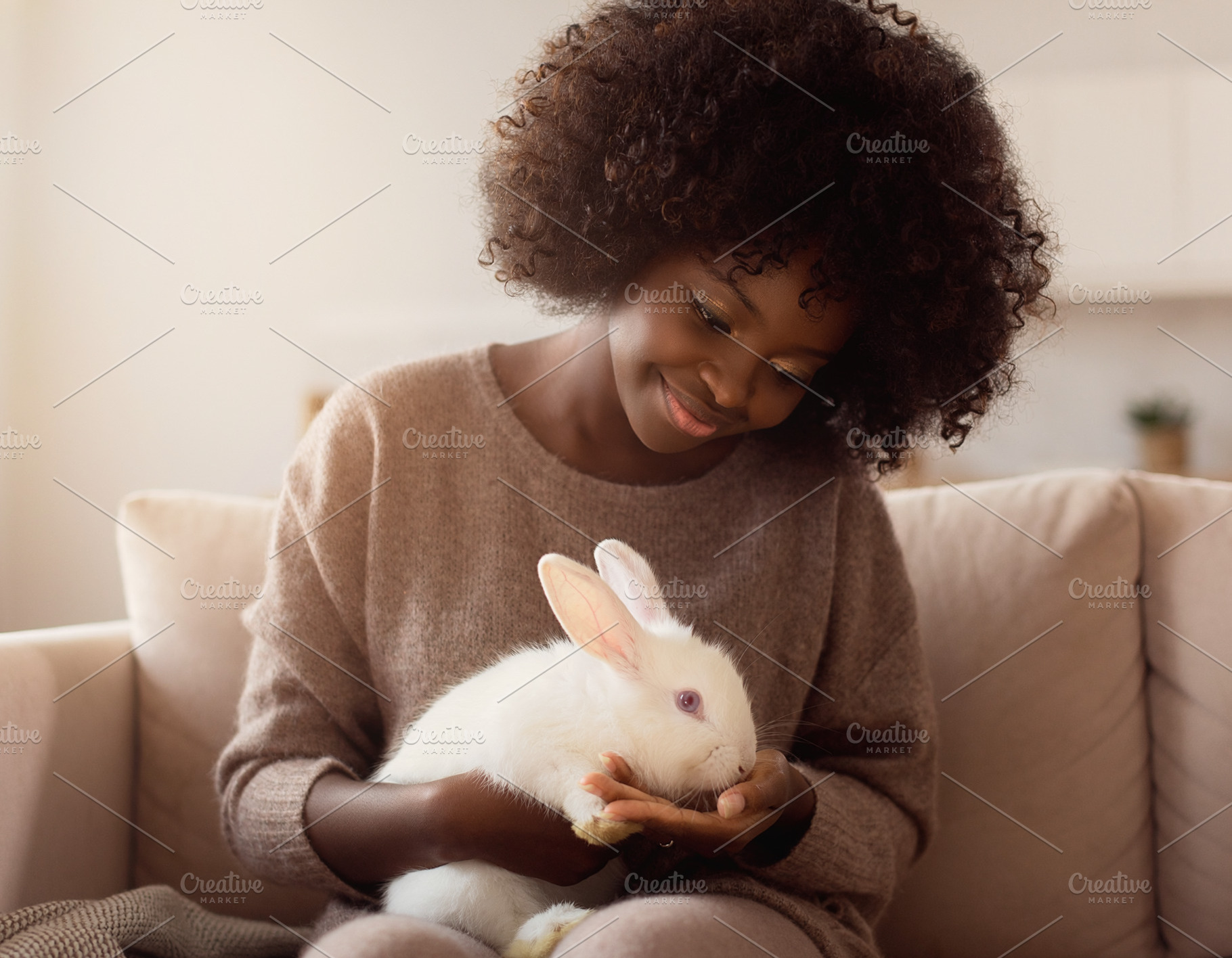 Young afro woman holding rabbit, a Person Photo by DanFLCreativo