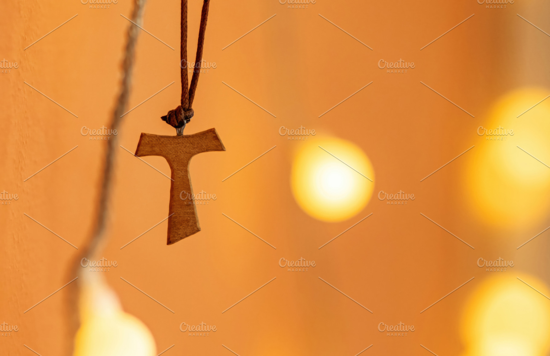 Tau cross hanging from a leather cord on a blurred background wi, a Photo by Antonio Gravante Market