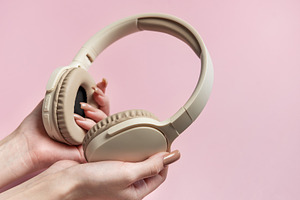 Woman holding wireless headphones on pink background, a Technology Photo by Olena Rudo