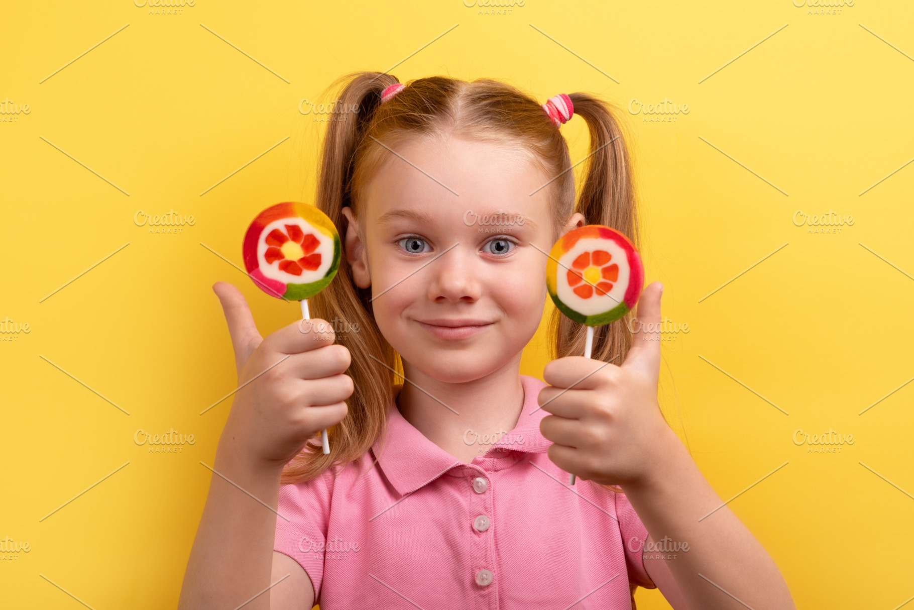 Happy young girl with pigtails holding two colorful lollipops an, a Person Photo by Ales Munt
