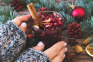 Woman's hands holding a cup of mulled wine between featuring wine