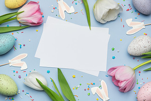 Easter eggs and tulips framing blank greeting card on pastel blu, a Holiday Photo by Olena Rudo