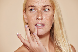 Woman with freckles touching her lip, a Beauty & Fashion Photo by Artem Varnitsin