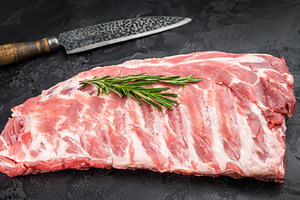 Raw pork spareribs slab with bone and butcher knife flat lay on