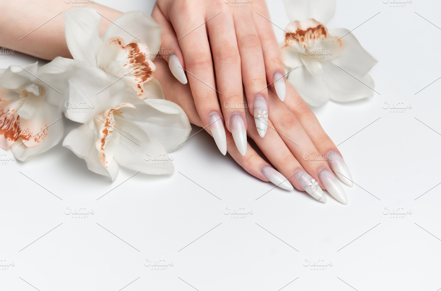 Elegant hands displaying long white almond nails with orchid flo, a Health & Medical Photo by Olena Rudo