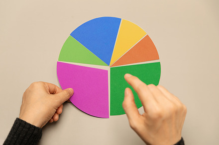 Hand selecting a segment on a colorful pie chart representing da