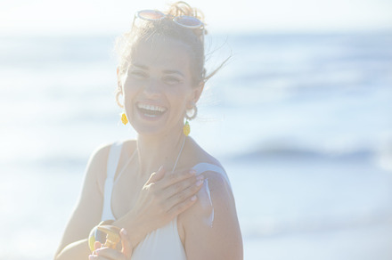 happy elegant woman in swimwear at beach applying sunscreen, a Person Photo by Alliance Images