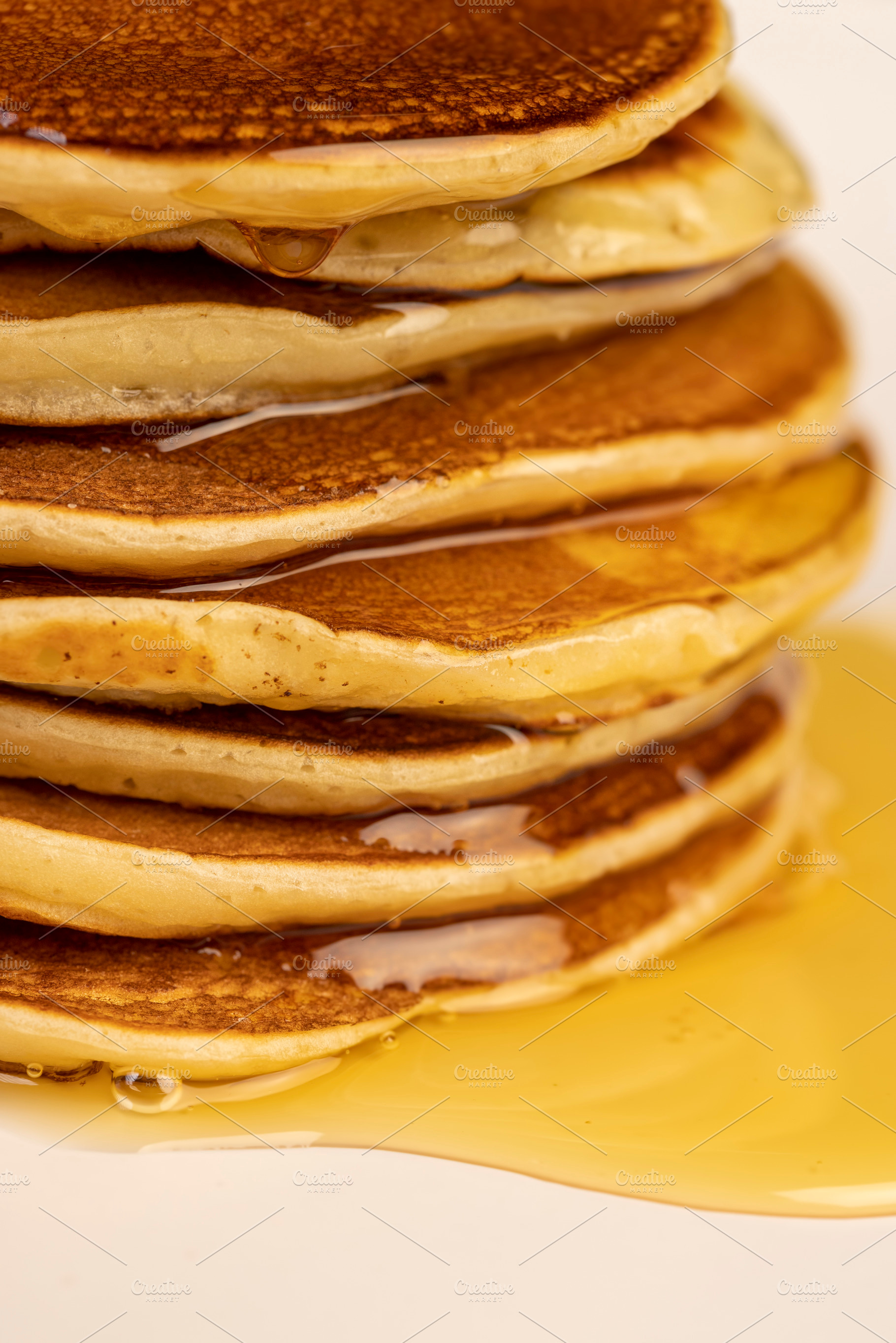a tower of small milk pancakes on a ceramic bowl with natural yellow bee honey, a Photo by rsoollAI