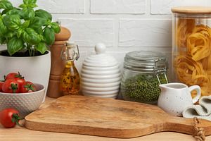 Empty wooden cutting board with various ingredients and utensils, a Food & Drink Photo by Olena Rudo
