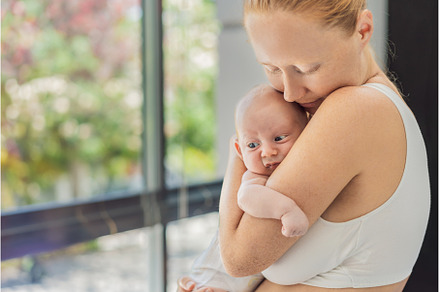 Mother gently hugging her baby at