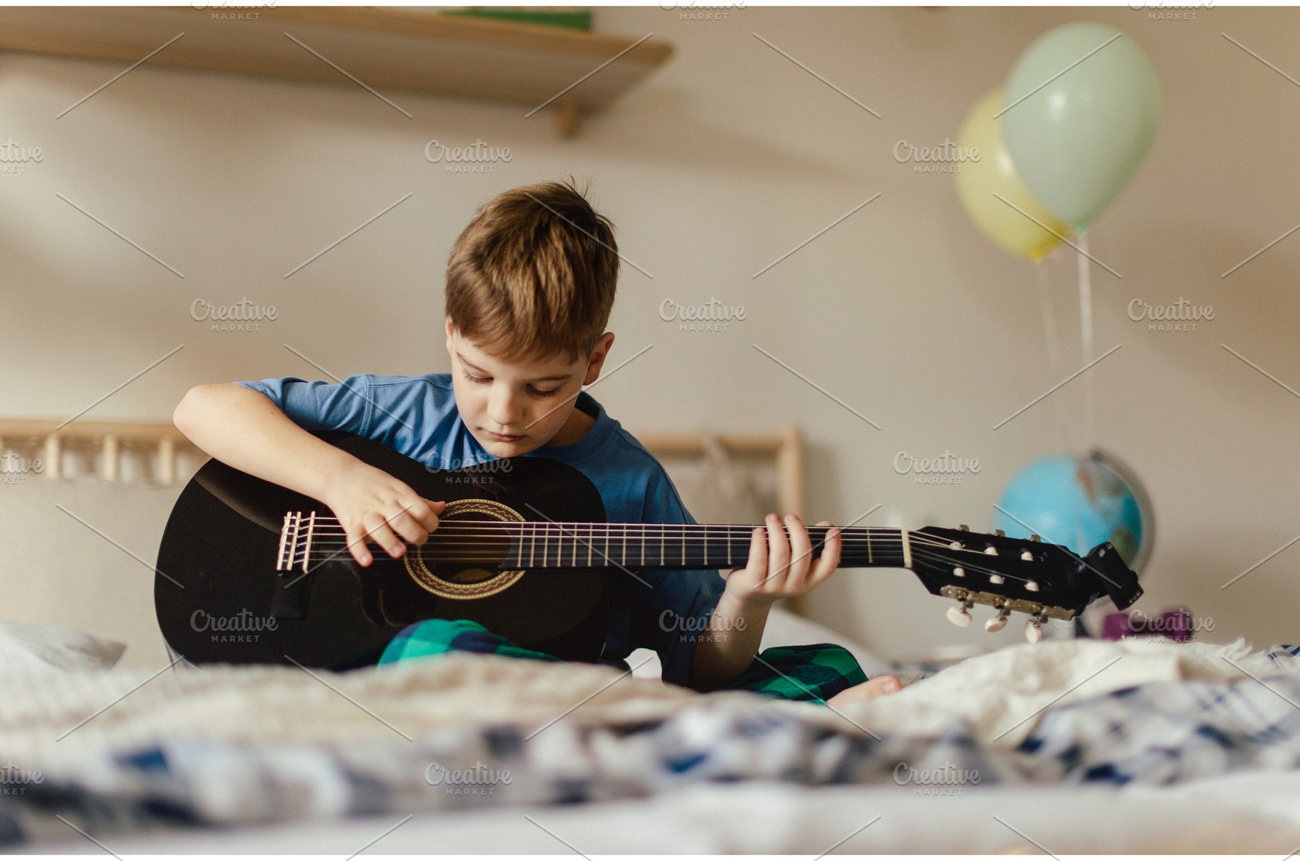 Happy boy playing on the guitar in, a School & Education Photo by HalfPoint