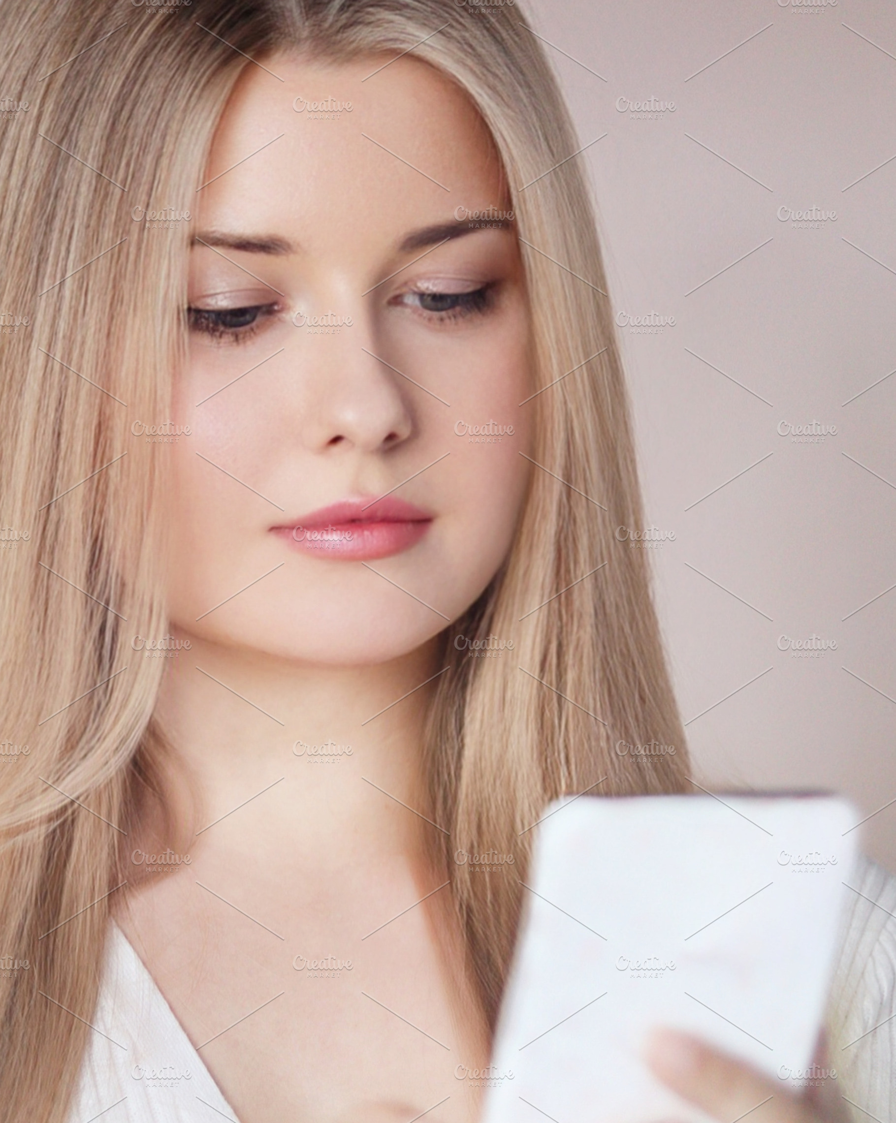 Young blonde woman using smartphone, browsing social media or texting with digi, a Person Photo by Studio ANNA