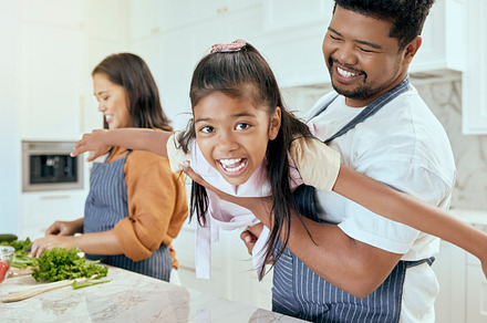 Mother, father and child play while cooking in the kitchen bonding, laughing and having fun happy family home, Smile, mama and dad enjoy playing with girl or kid in a healthy dinner meal preparation, a Photo by Peopleimages.com