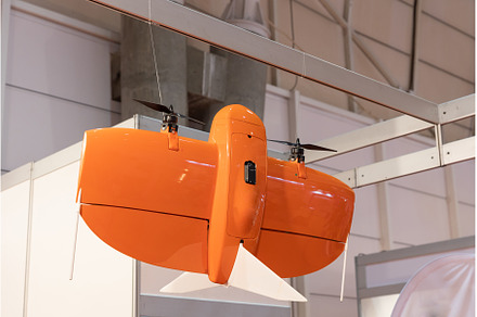 Orange drone at the modern expo, a Technology Photo by Barcelona_dreams