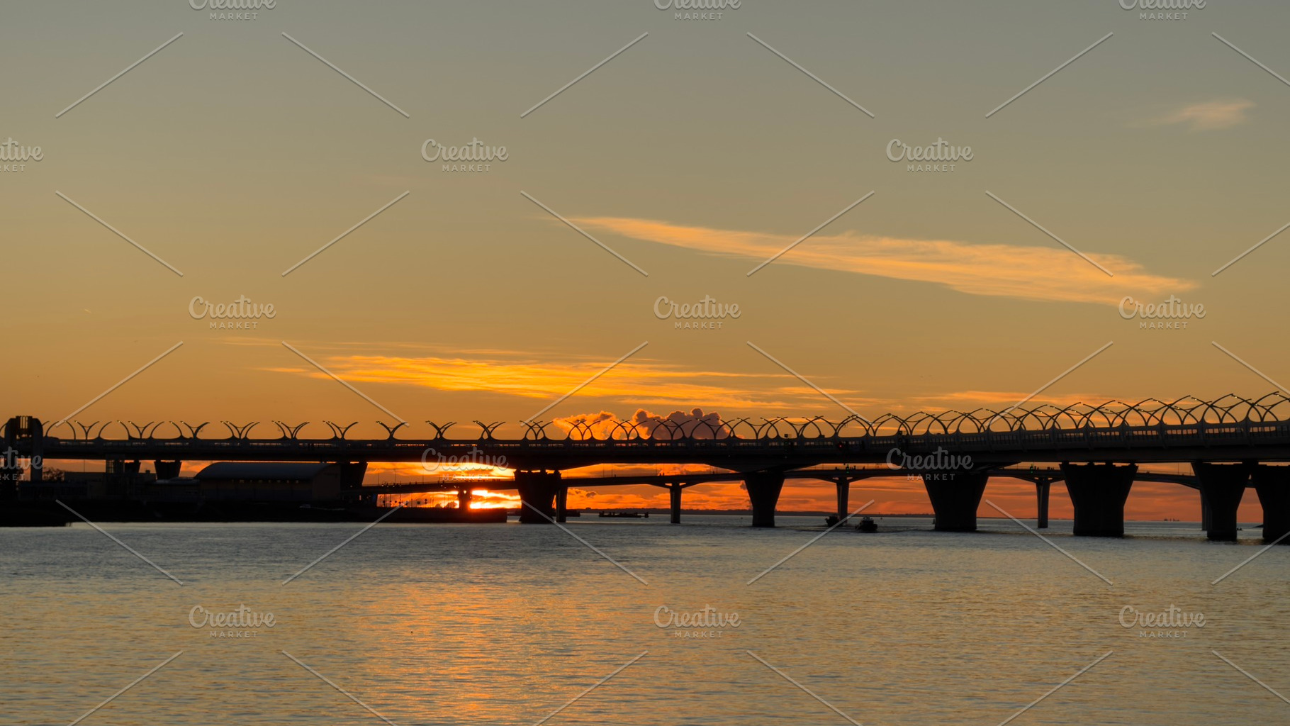 A serene sunset over a river with a bridge silhouetted against the colorful sky, a Nature Photo by Textures & Backgrounds