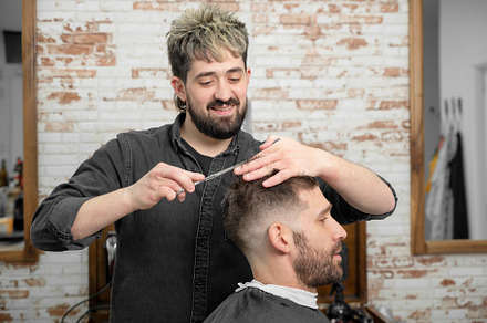 Barber cutting hair with scissors to a handsome young man ., a Person Photo by david.herraez.calzad