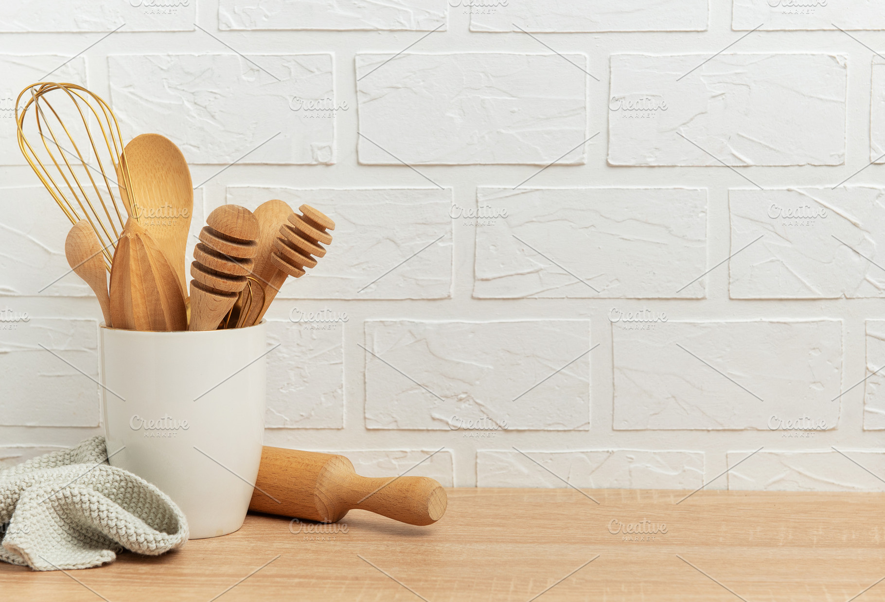 Kitchen utensils resting on wooden countertop by white brick wal, a Food & Drink Photo by Olena Rudo