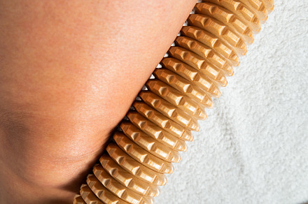 Hand holding a wooden massage roller during maderotherapy on the