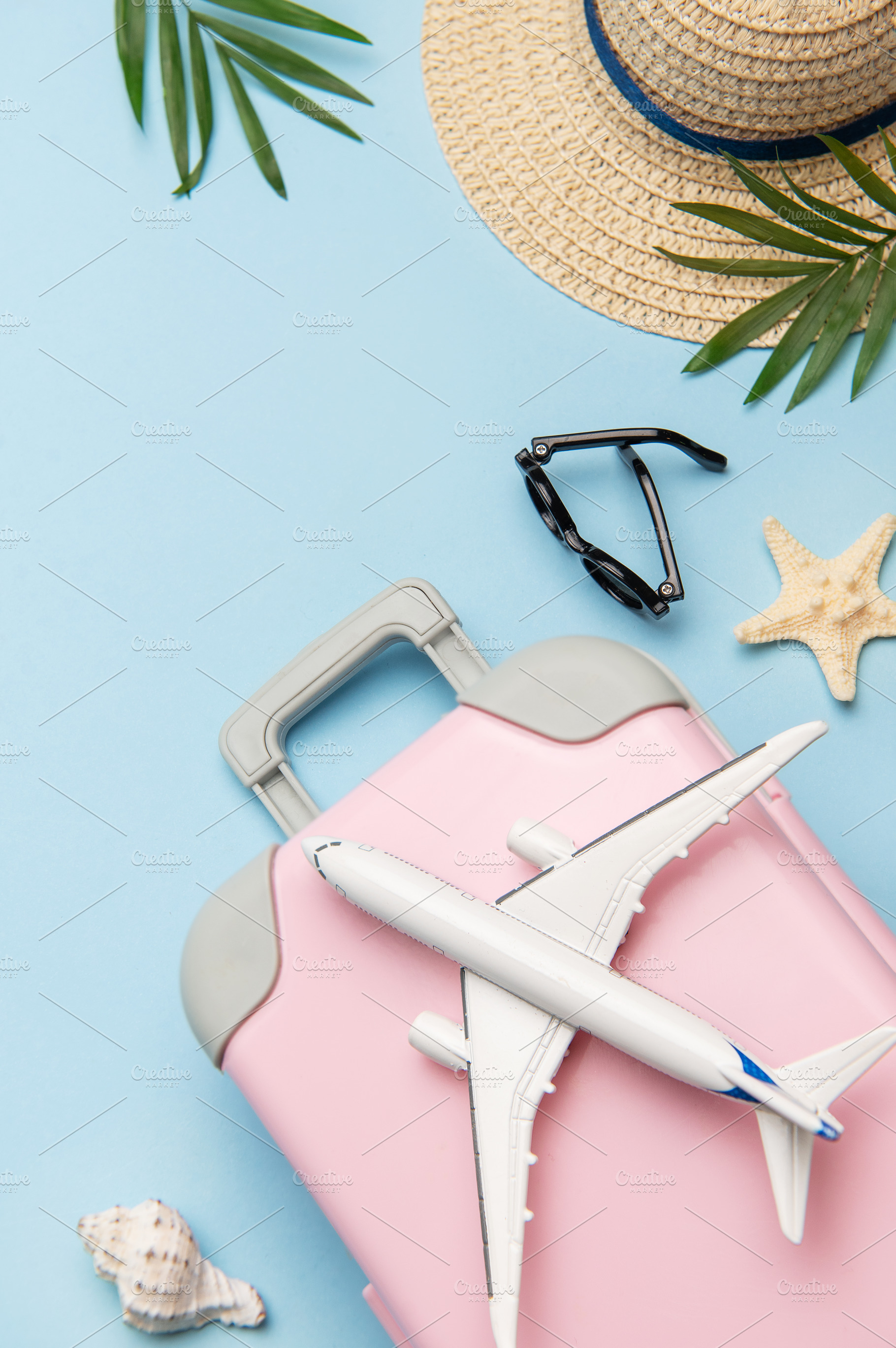 Pink suitcase with toy airplane, sunglasses, straw hat, seashell, a Holiday Photo by Olena Rudo