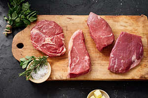 Selection of raw rib-eye, roast beef, flank and rump steak on a wooden cutting, a Food & Drink Photo by Asya Nurullina