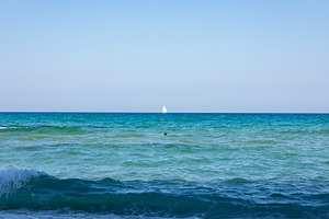Minimalist seascape with a small white sailboat on the horizon under a clear bl, a Transportation Photo by Ales Munt