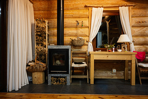 Cozy rustic living area with wood stack and fireplace for warmth, a Photo by AS photostudio