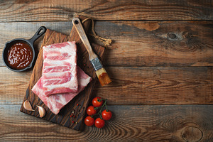 Raw pork ribs with spices, salt and rosemary on dark wooden background, a Food & Drink Photo by Budarinphoto