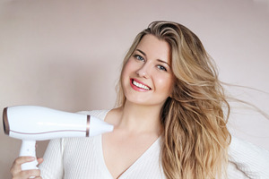 Happy young woman blow drying her long blonde hair for beauty, s, a Person Photo by Studio ANNA