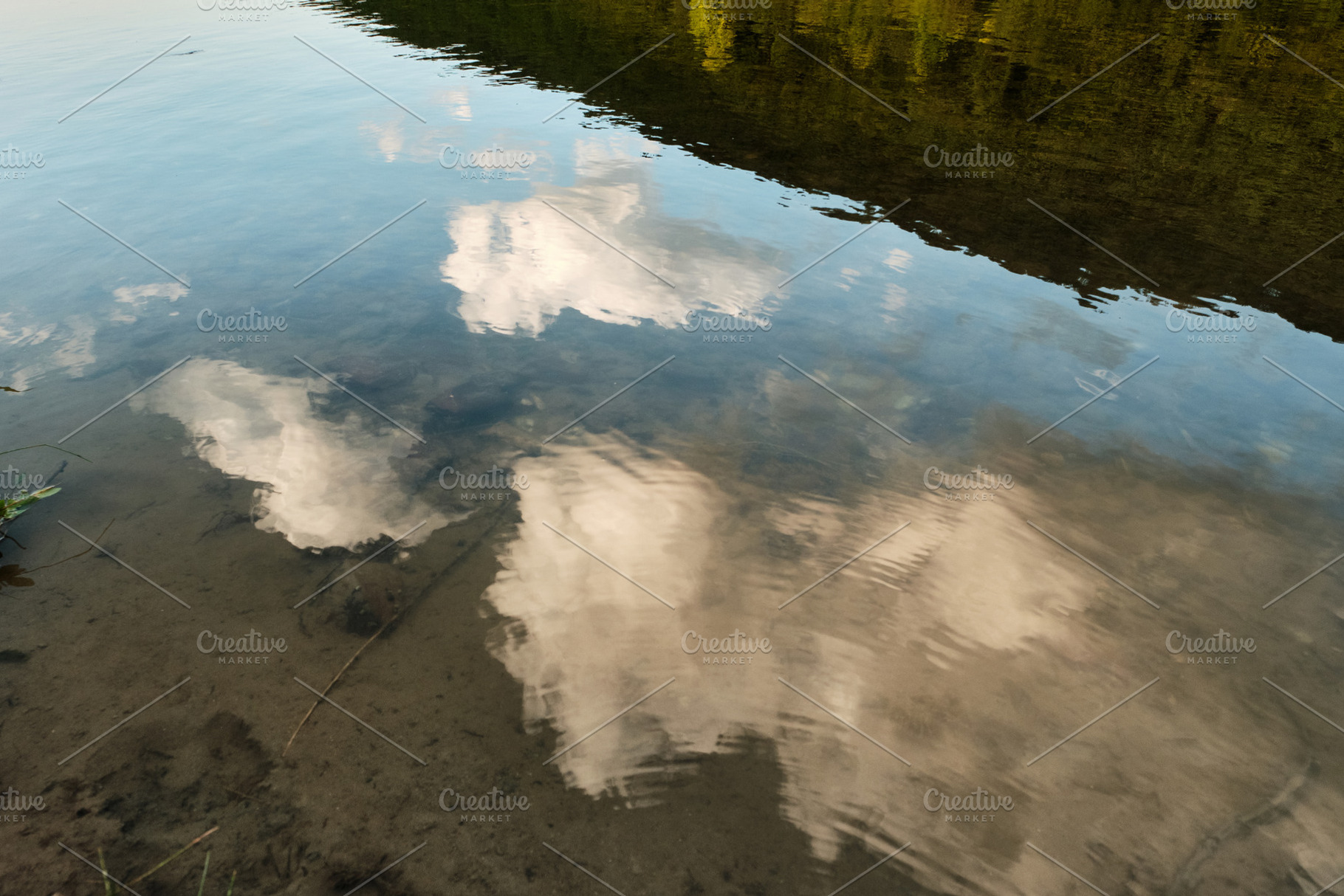 Clouds and green shore reflected in clear shallow river water. Abstract water r, a Nature Photo by Rohan Photography