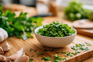 Freshly chopped herbs in a bowl ready for culinary use in a bright kitchen sett, a Food & Drink Photo by AlyaAnd