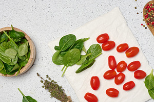 Wooden bowl with spinach, cherry tomatoes, wooden spoon with spi, a Food & Drink Photo by ndanko