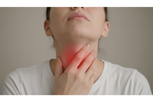 Woman touching her neck with glowing, a Health & Medical Photo by Igor Tichonow