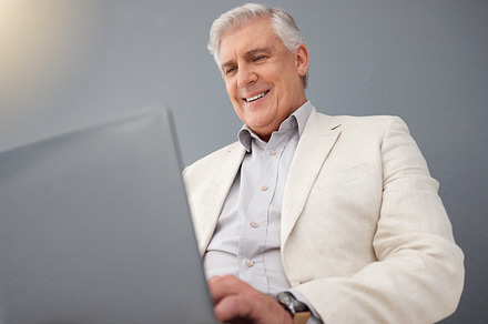 Senior business man, laptop and studio background for planning, online strategy and email website. Happy executive manager working on computer technology, corporate management and professional smile, a Photo by Peopleimages.com