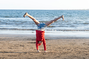 Girl doing cartwheel at the beach in Santa hat, a Person Photo by etorres69