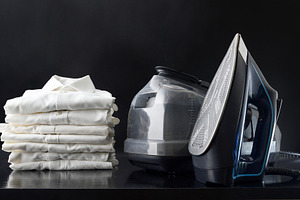Domestic ironing station on black table with shirts black backgr, a Technology Photo by Davizro's Market