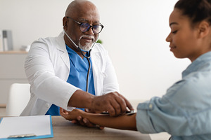 Doctor checking measuring pressure on patient's hand pulse, a Photo by Prostock-Studio