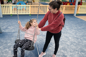 Mother pushing her daughter on a swing at a playground, a Person Photo by etorres69