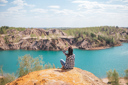 Young woman sitting on the top of mounting and feeling free and looking at the, a Person Photo by travnikovstudio