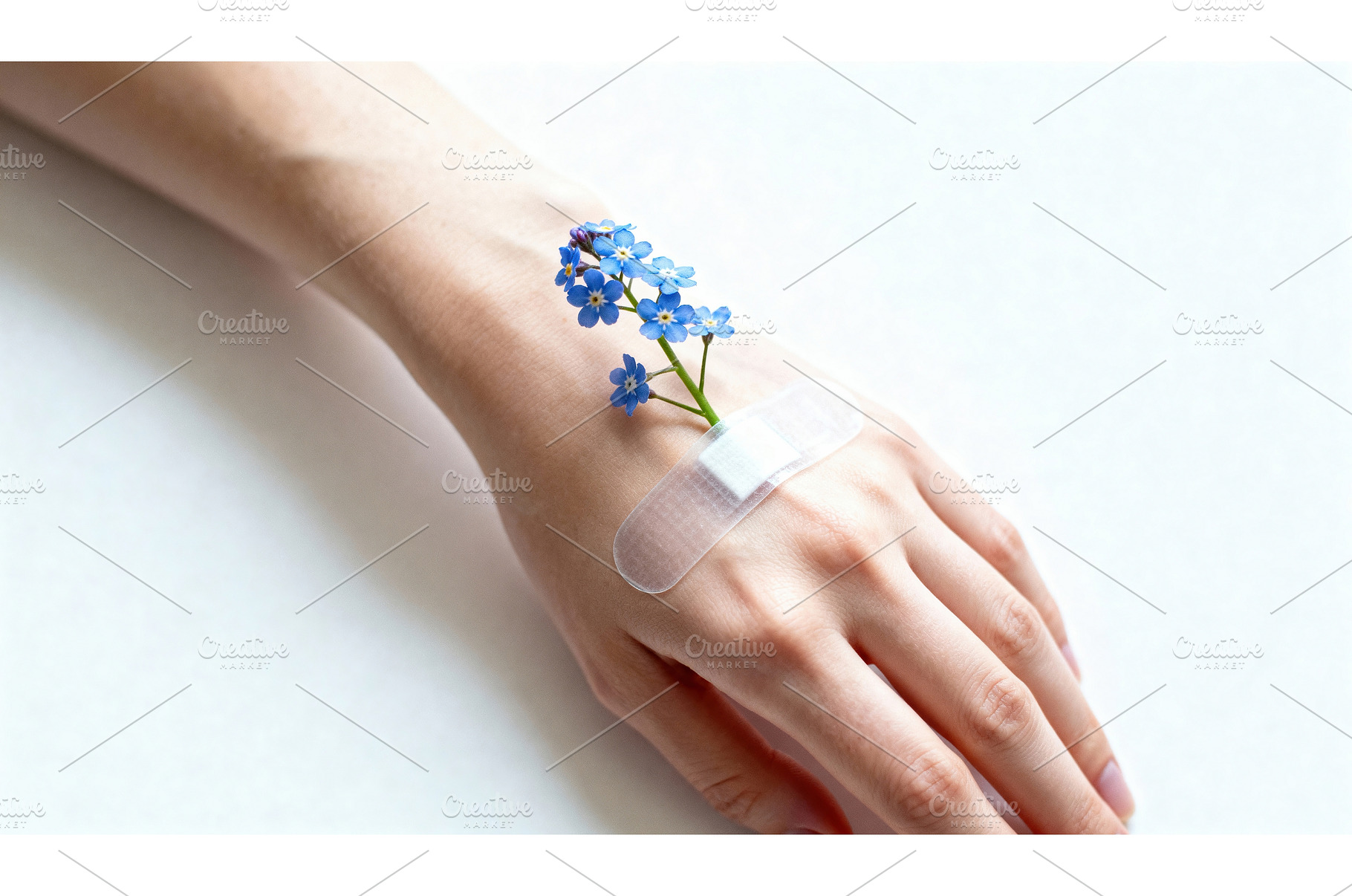 Hand with bandage and blue forget-me, a Health & Medical Photo by tilialucida