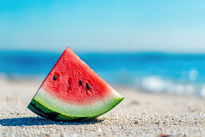 Ripe watermelon slice resting on sandy beach with ocean views and bright blue s, a Food & Drink Photo by AlyaAnd