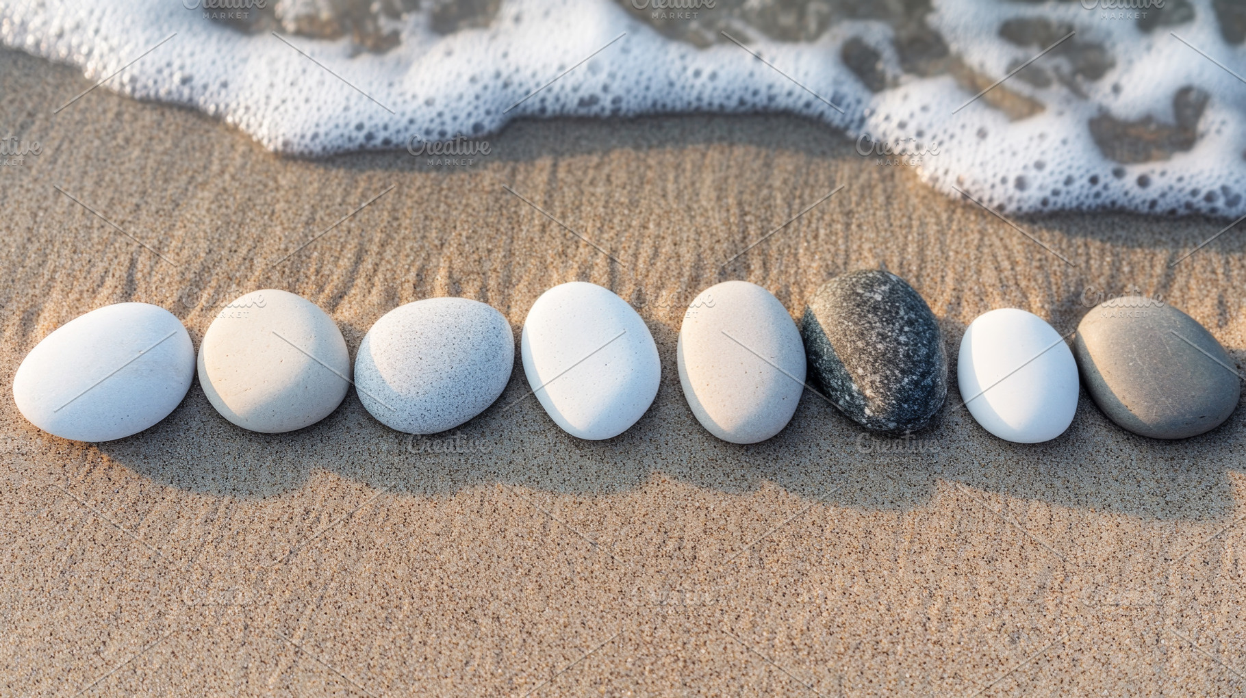 Assorted pebbles aligned on a beach with a calm ocean backdrop, an Abstract Photo by Natalia Klenova's Shop