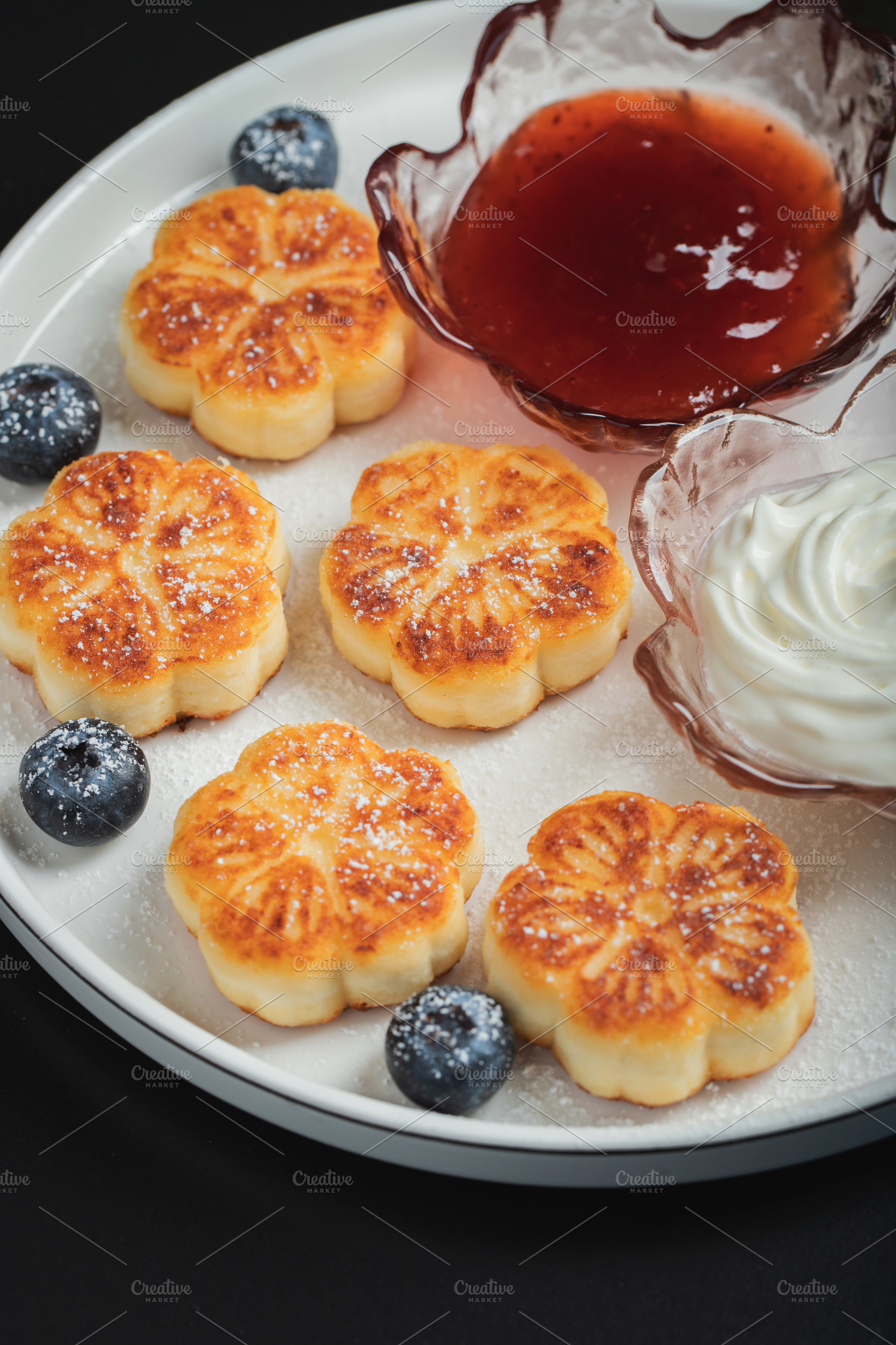 Cottage cheese pancakes, syrniki, curd fritters decorated with strawberry and r, a Food & Drink Photo by Budarinphoto