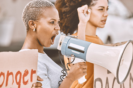 Protest, angry and black woman with a megaphone as leadership for social change, justice and freedom from government. Conflict, fight and African girl shouting during a rally against racism in city, a Photo by Peopleimages.com