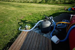 Pool equipment setup in grassy yard with pipes and filtration system outdoors, a Photo by AS photostudio