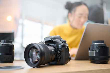 Photography camera, laptop and photographer editing photoshoot, focus on digital art or retouching artistic photo. Studio, creative vision and professional Asian woman working on creativity process, a Photo by Peopleimages.com