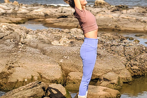 Woman stands on rocky coast holding a yoga pose with arms raised, a Health & Medical Photo by DanFLCreativo