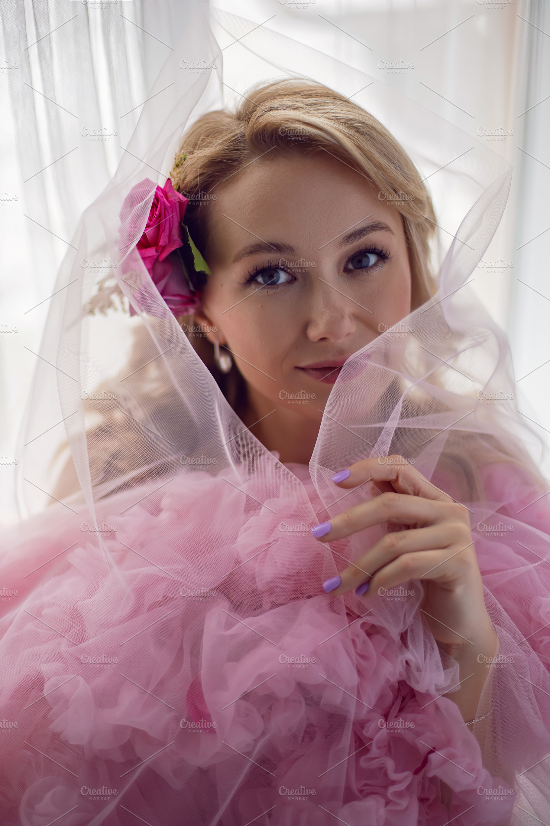 portrait of a fashionable blonde woman in a pink dress and rose flower in her h, a Person Photo by SaulichPhoto
