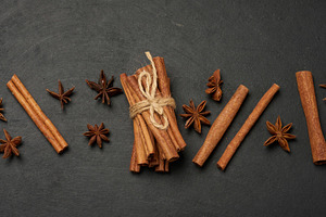 Cinnamon sticks and star anise are scattered on a dark, textured, a Food & Drink Photo by ndanko