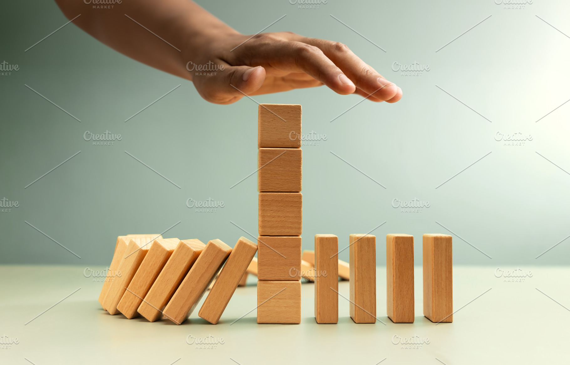Hand stopping falling dominoes, Economic crisis prevention, a Photo by salmon.black