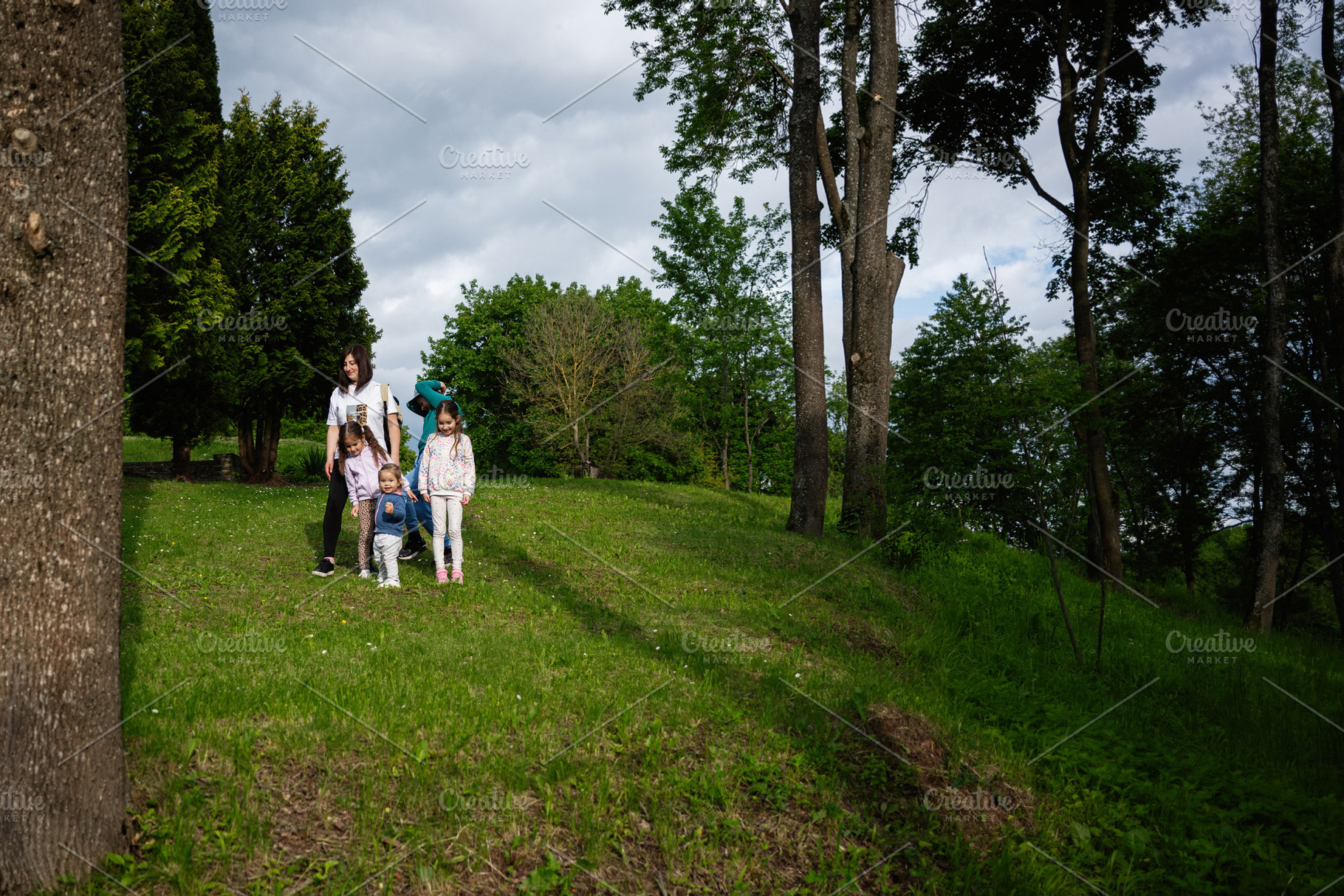 Family walking together in a lush green park on a sunny day, a Person Photo by AS photostudio